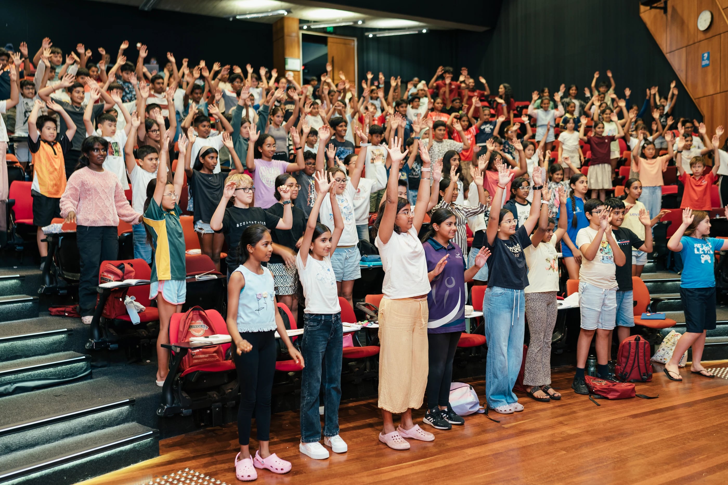 A room of students joining in a hands-up activity